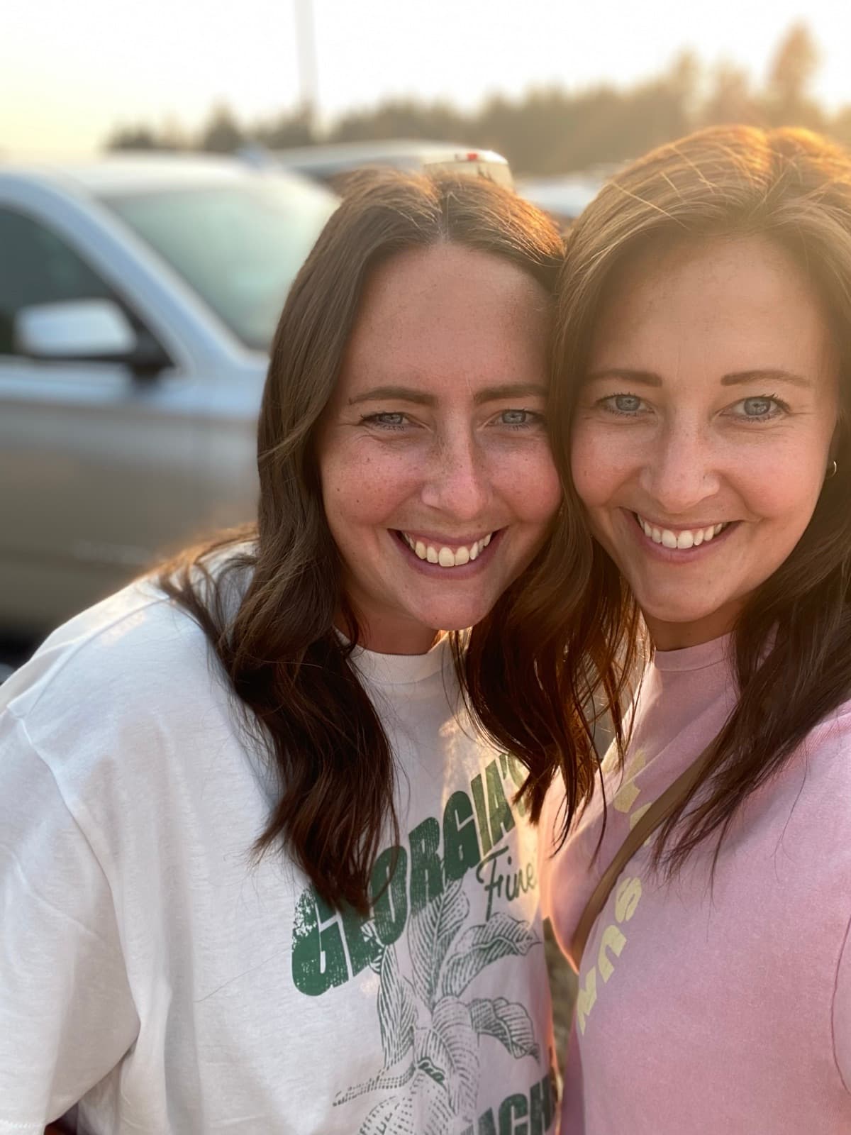 Lauren and Chelsea, the two sisters, smiling together in golden evening light