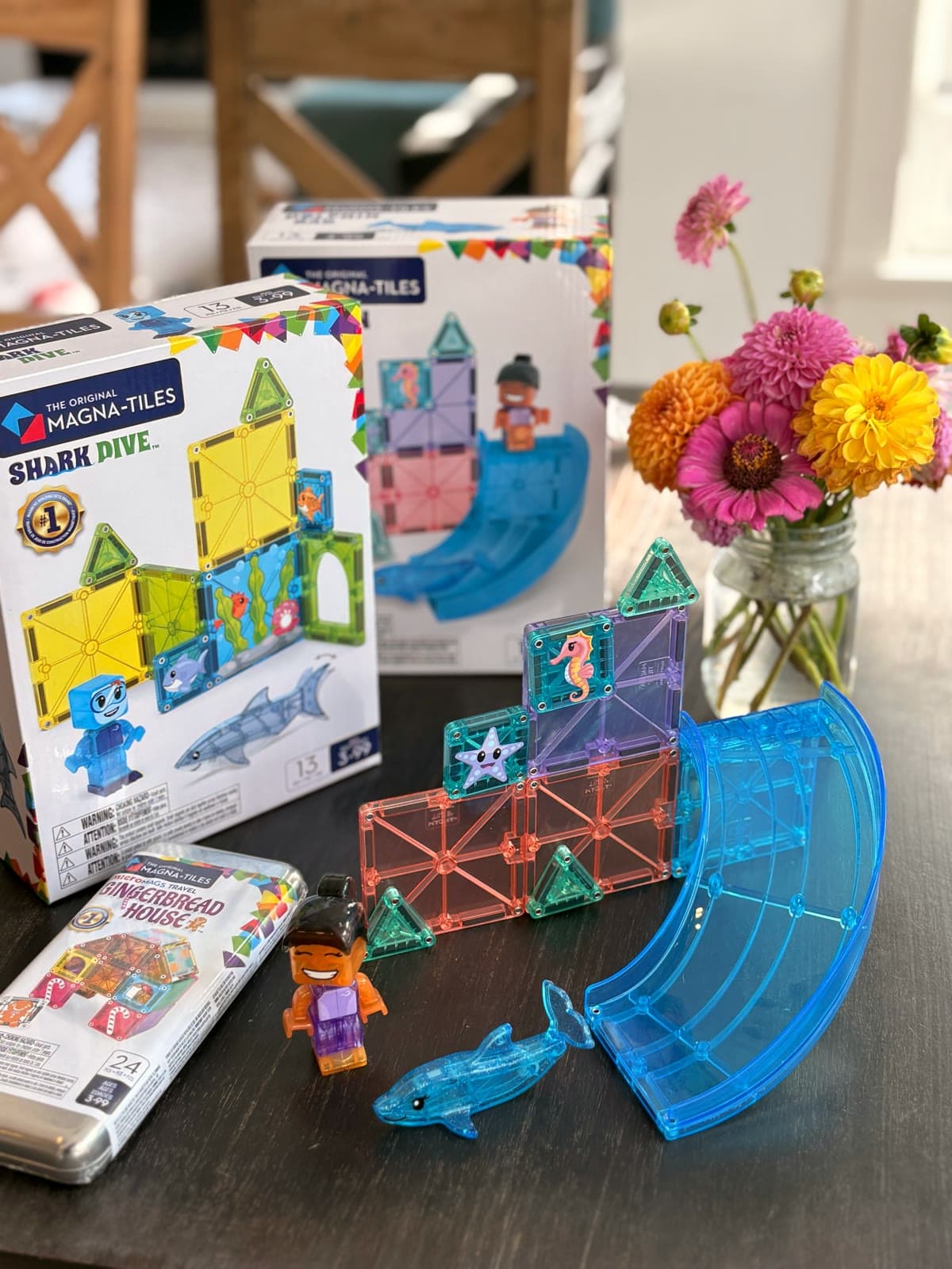 A small Magna-Tiles build on our kitchen table with a seahorse tile, a starfish tile, a blue slide and a dolphin, with the Shark Dive box behind it