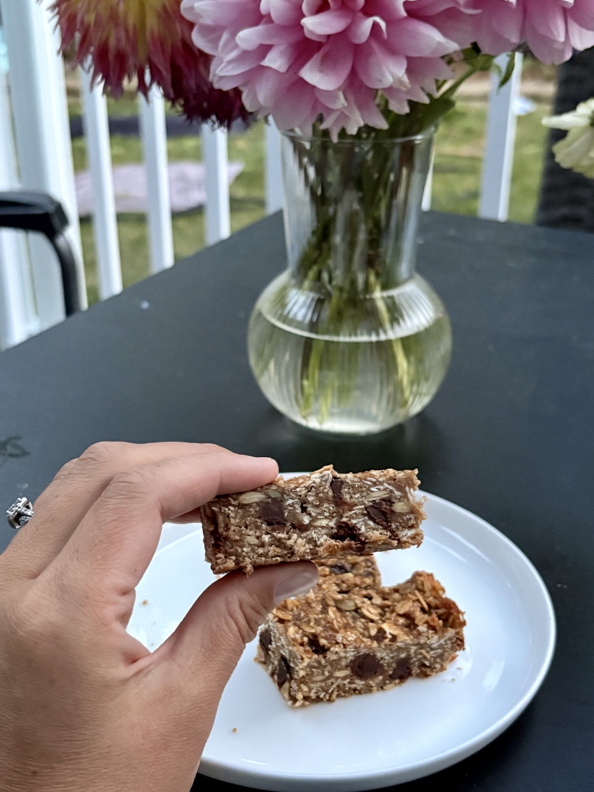 A soft granola bar held up close, full of oats and chocolate chips